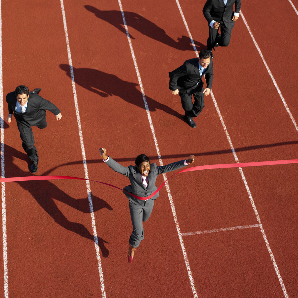 Businesswoman Crossing the Finish Line Ahead of Businessmen