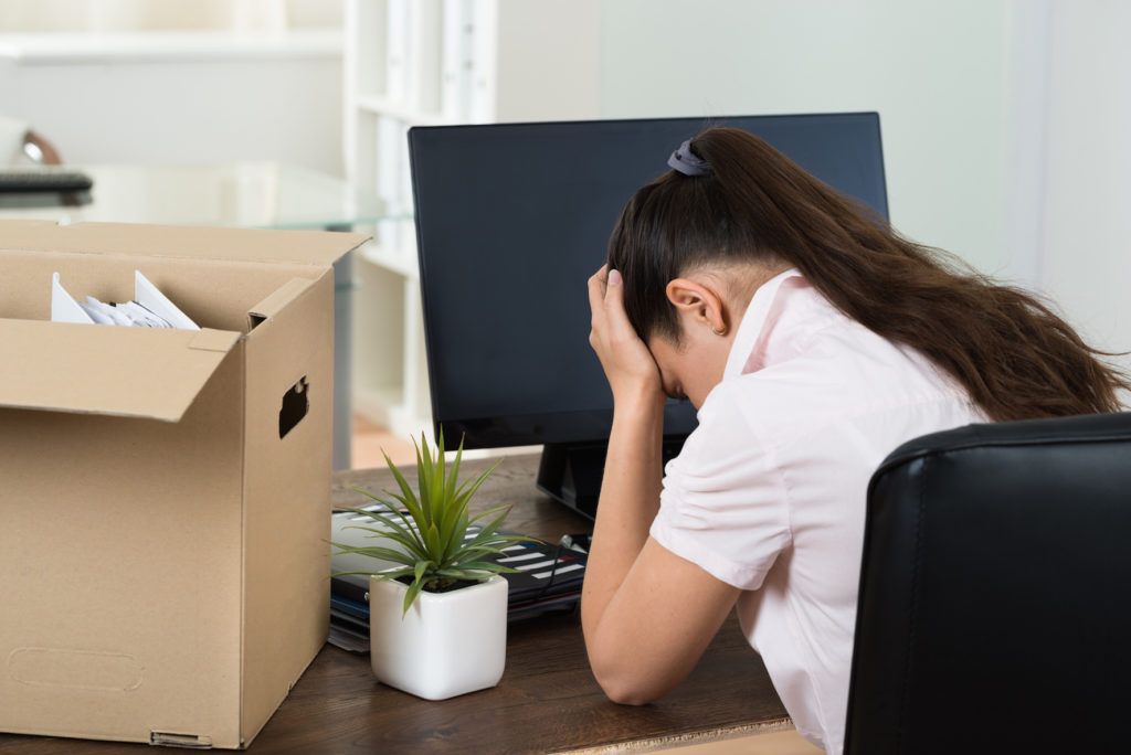 Dismiss Young Businesswoman With Belongings Sitting At Desk In Office